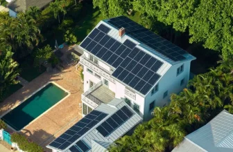 Aerial view of a white house with installed solar panels and a swimming pool.