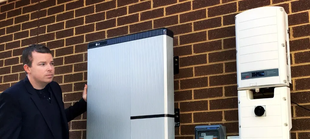 7 Best Powerwall Alternatives 3 Man standing near LG Chem RESU Solar Battery mounted on the wall.